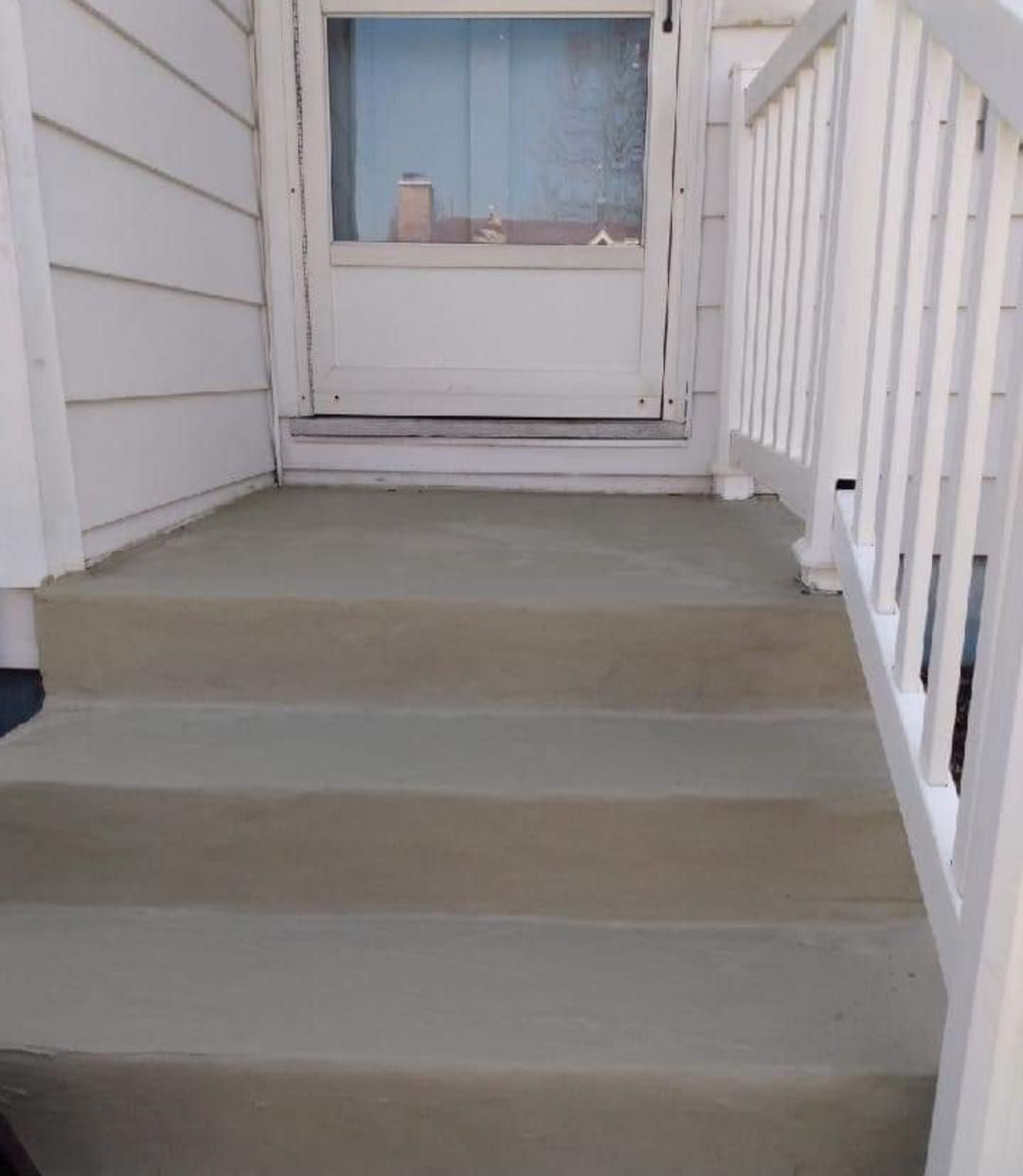 A set of stairs leading up to a porch with a white railing.