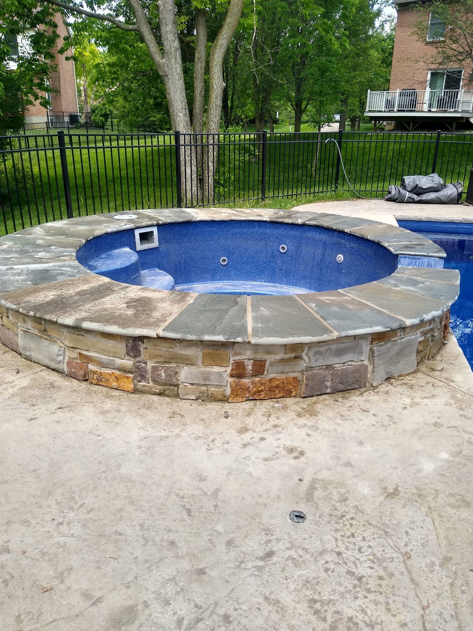 A round hot tub is sitting next to a swimming pool.