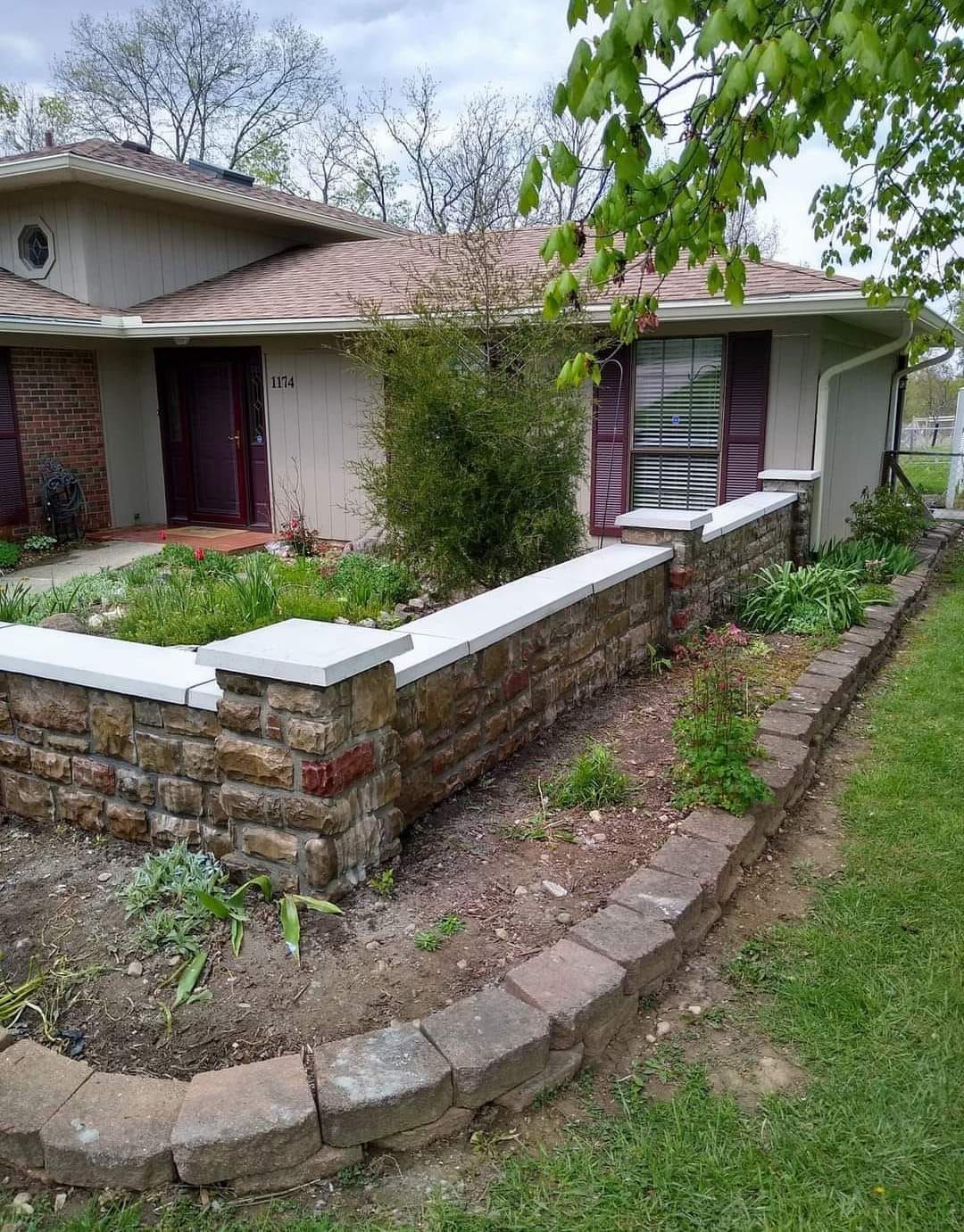 A house with a stone wall in front of it.