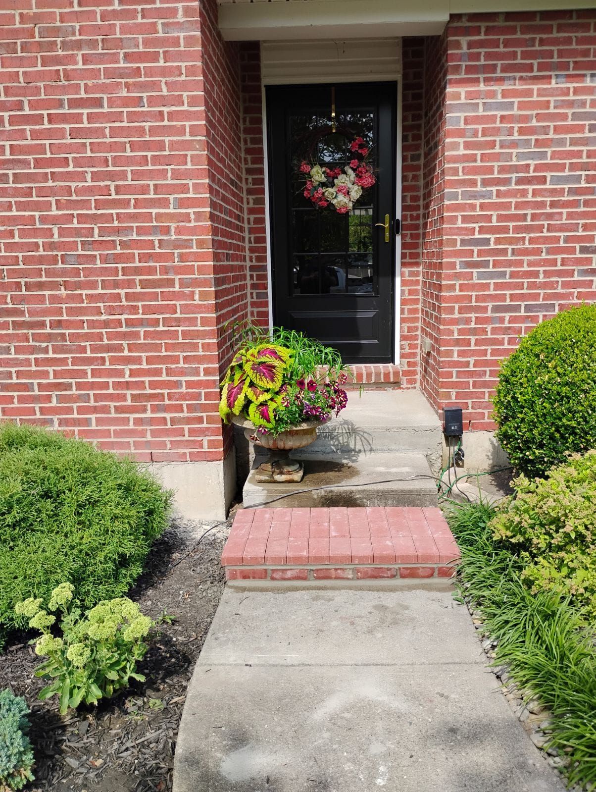 A brick house with a black door and a walkway leading to it.