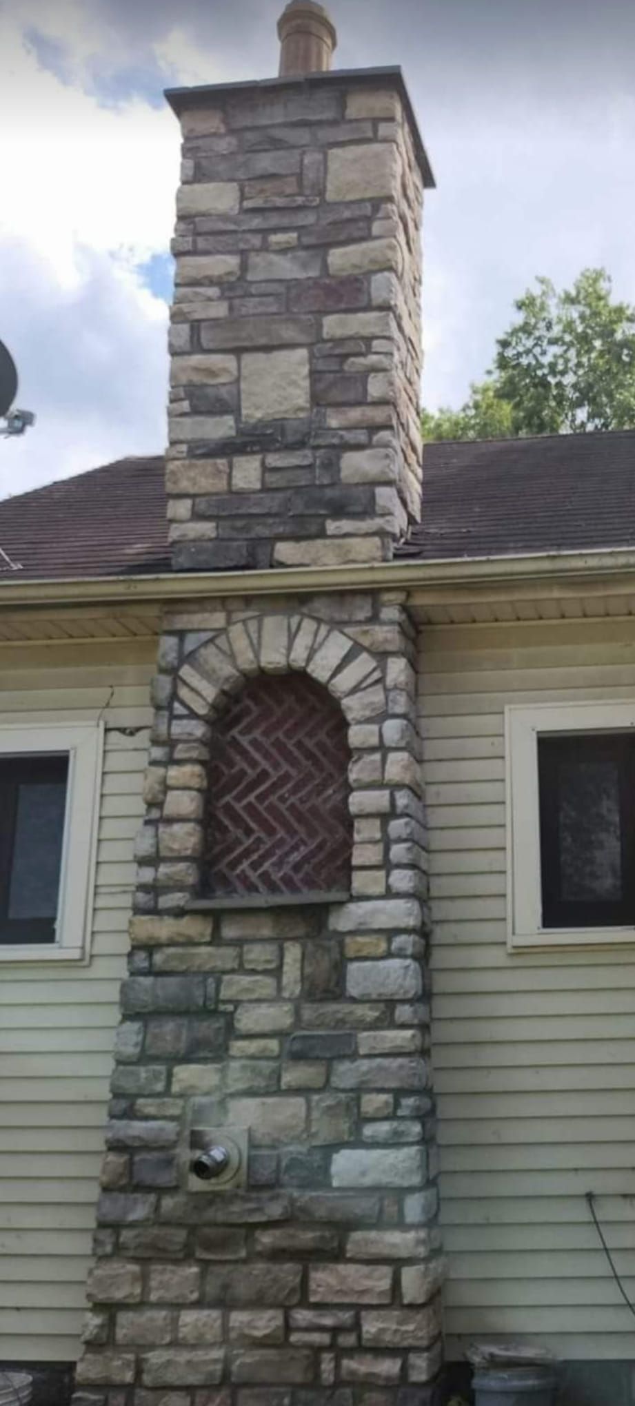 A large stone chimney is on the side of a house.