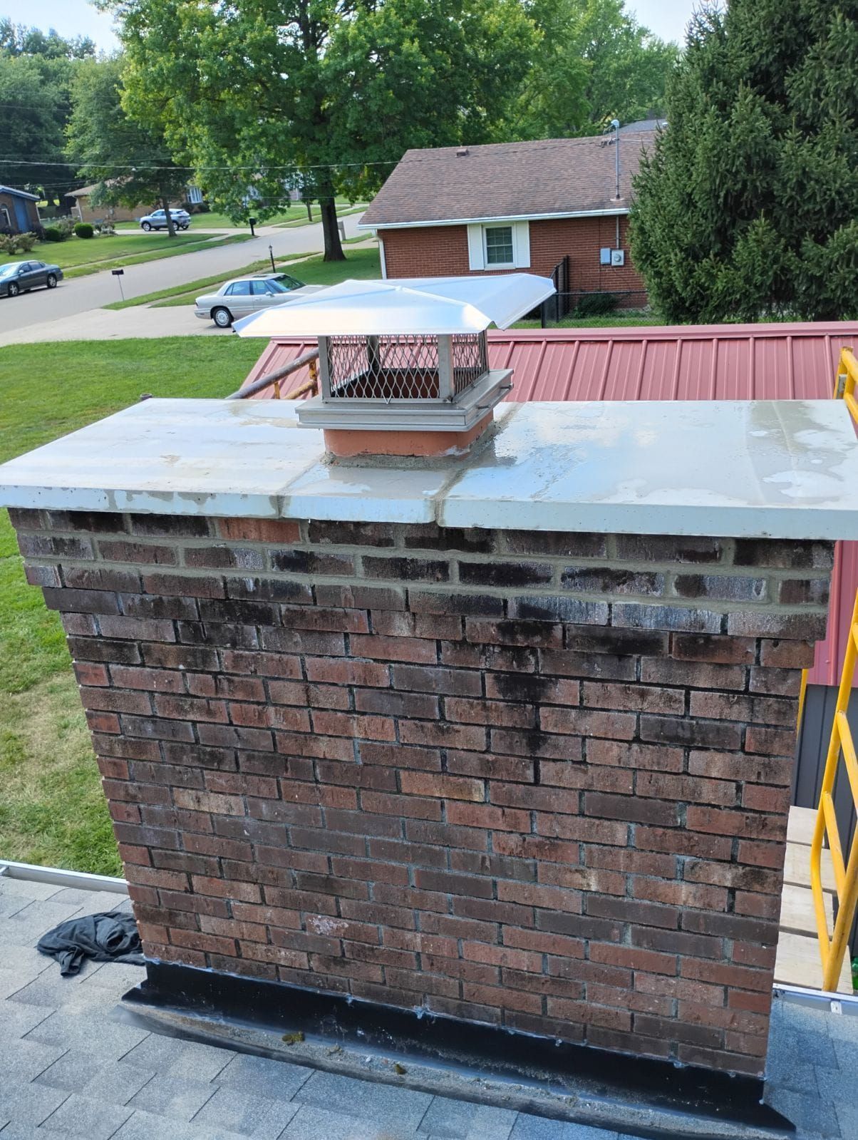 A brick chimney on top of a roof next to a house