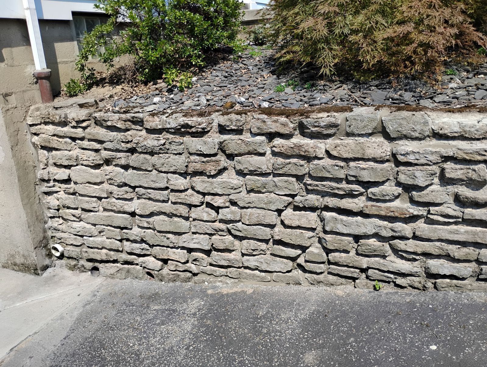 A stone wall is sitting on the side of a road.