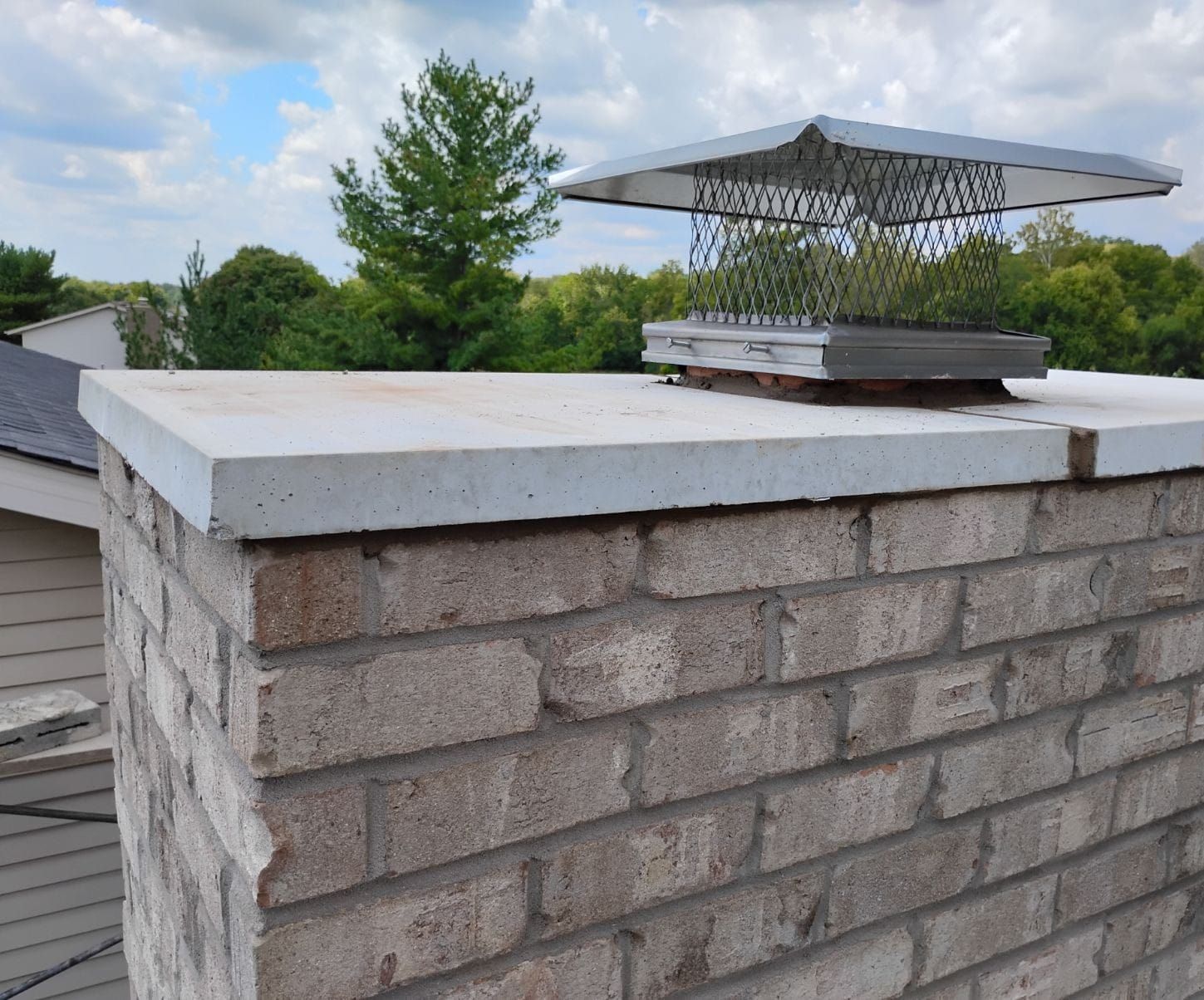 A brick chimney with a metal cover on top of it