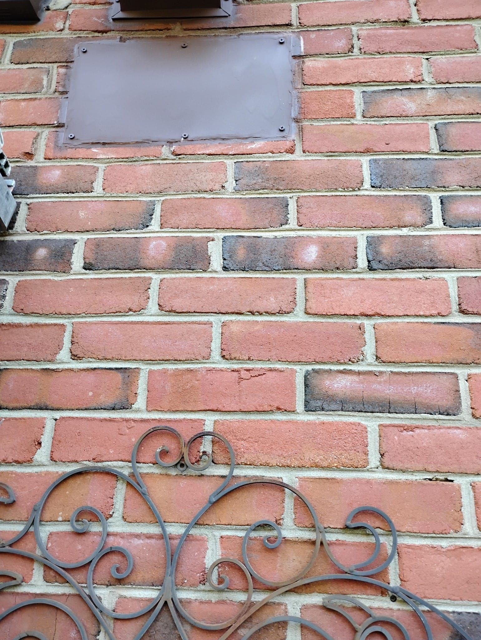 A close up of a brick wall with a wrought iron fence