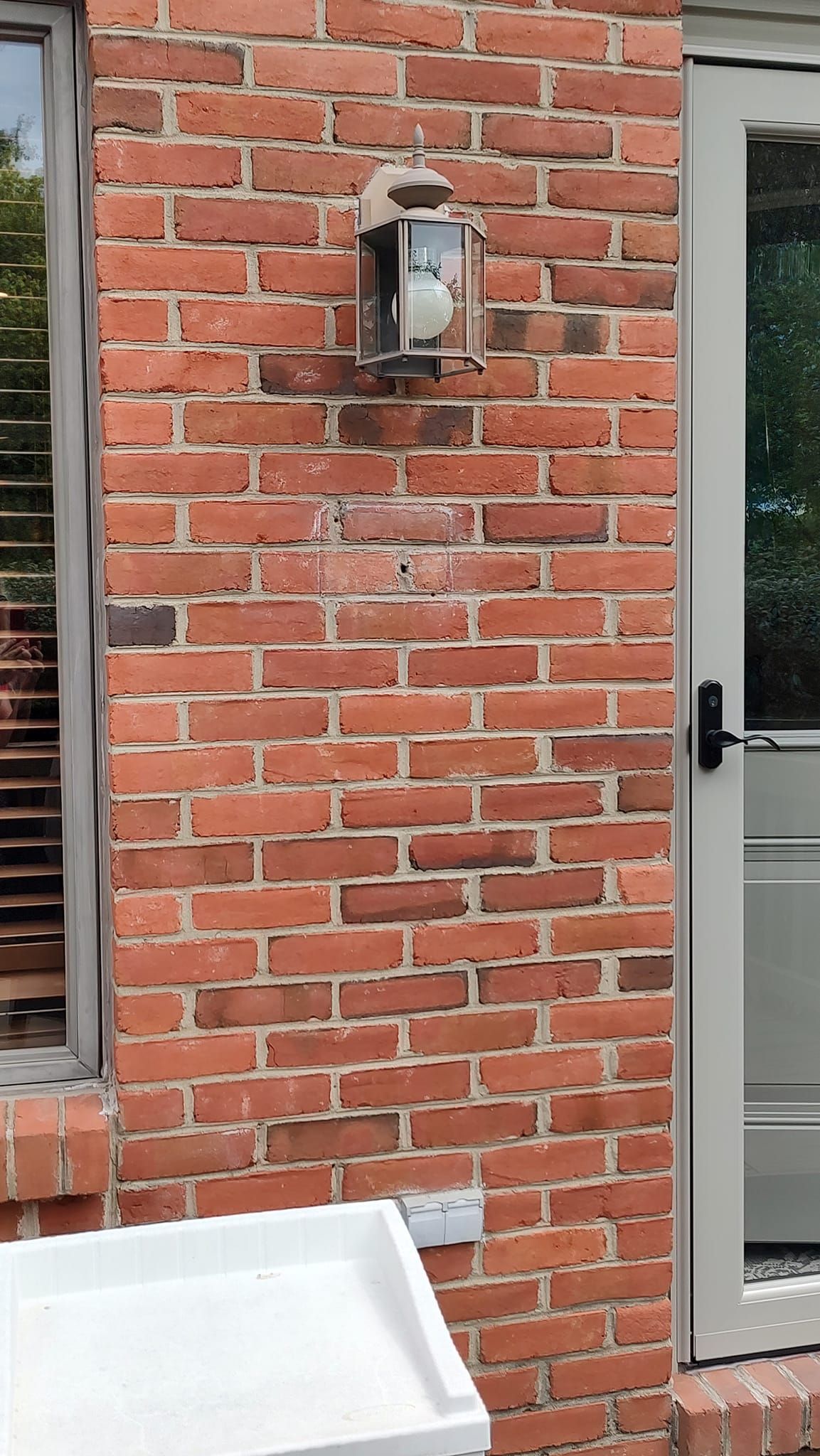 A brick wall with a white door and a window.