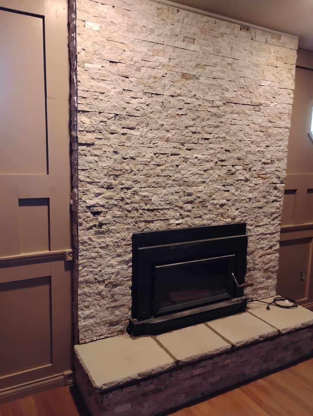 A fireplace in a living room with a stone wall