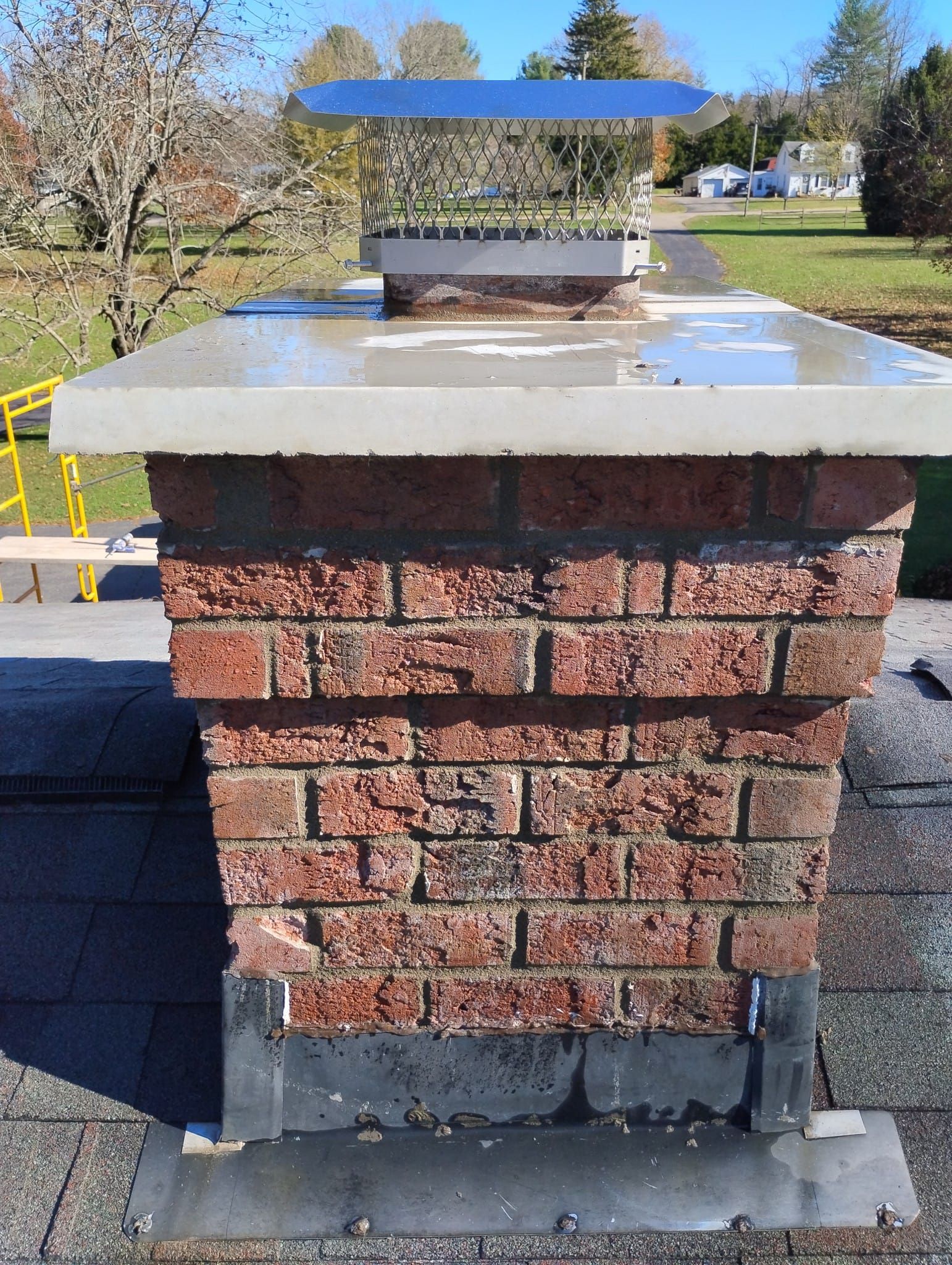 A brick chimney is sitting on top of a roof.