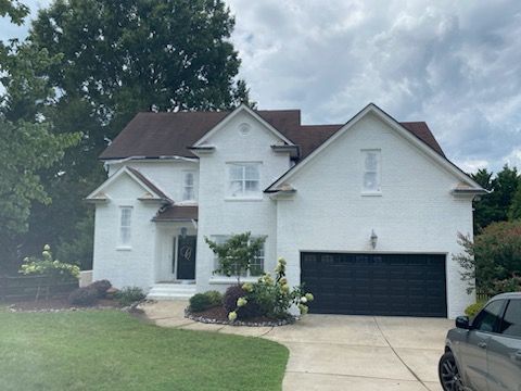 A white house with a black garage door and a car parked in front of it.
