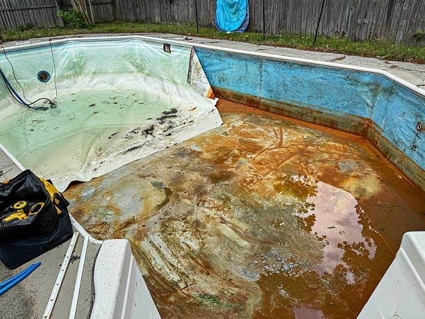 Empty, stained concrete swimming pool undergoing an acid washing and stain removal renovation process.