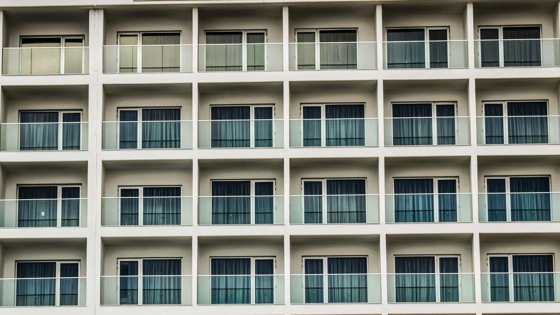 A large apartment building with lots of balconies and windows.