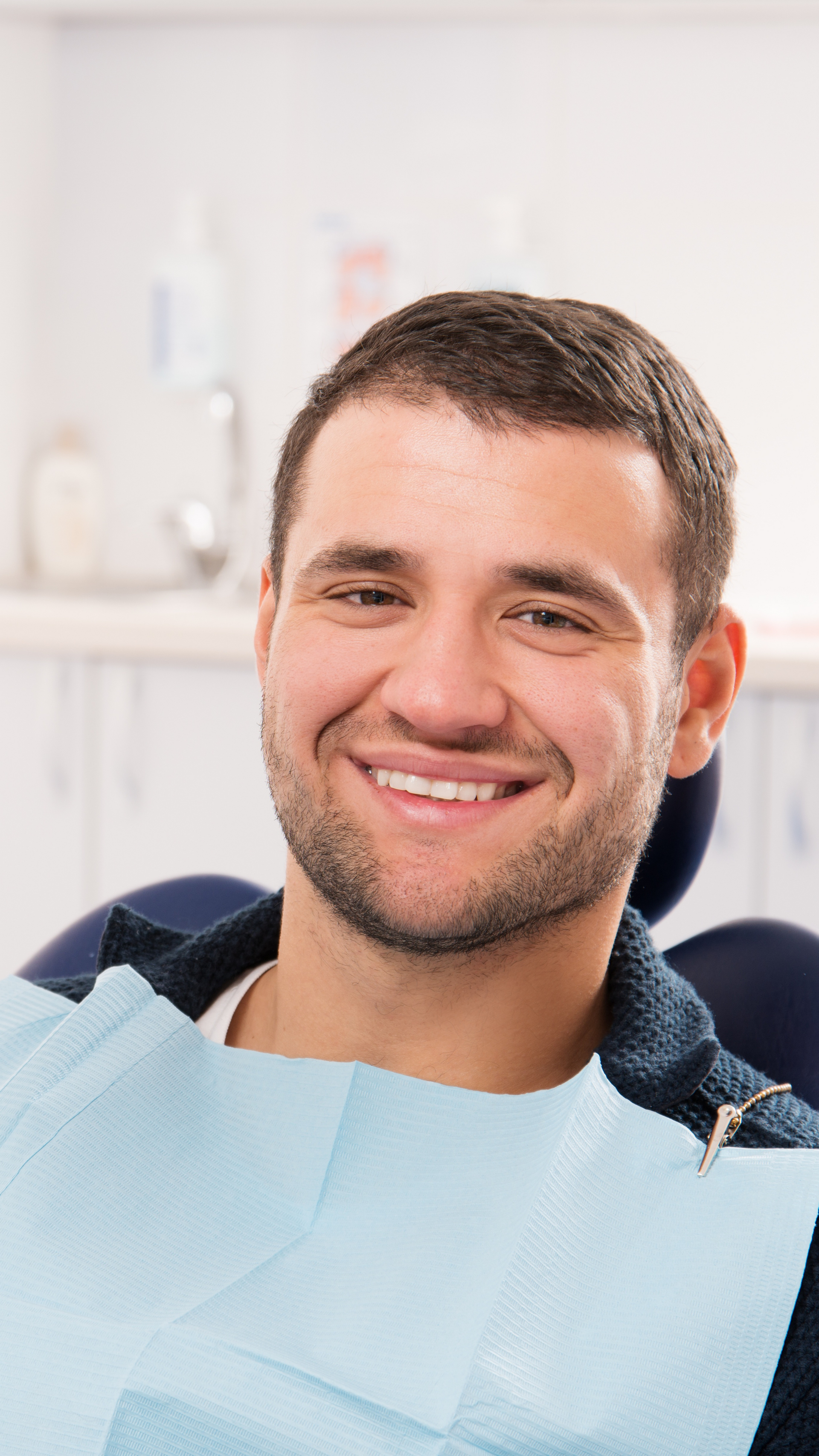 A man is smiling while sitting in a dental chair.