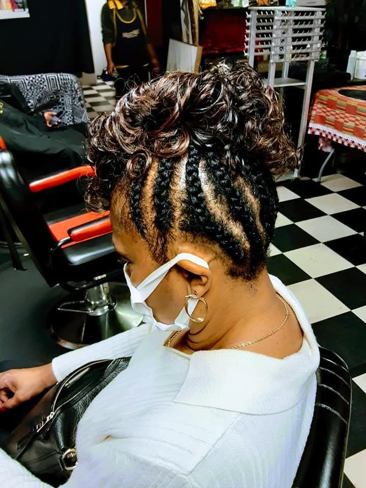 A woman wearing a mask is sitting in a chair in a salon.