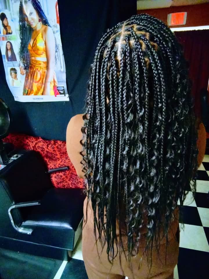 A woman with braids in her hair is standing in a salon.