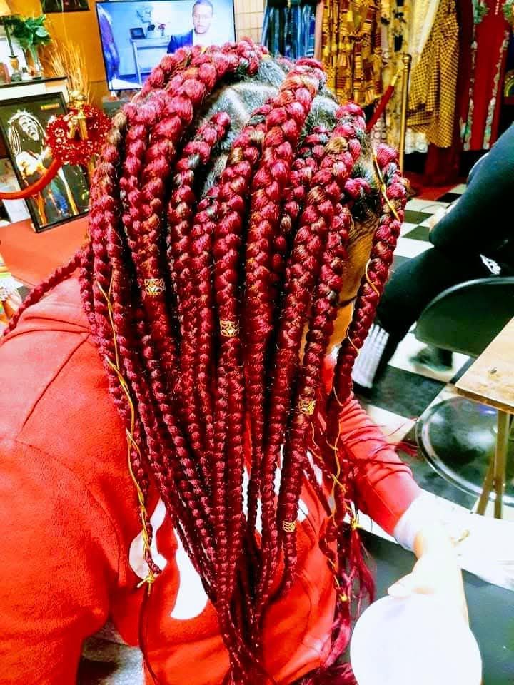 A woman with red braids is sitting in a chair in a salon.