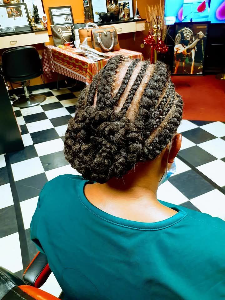 A woman is sitting in a chair with braids in her hair.