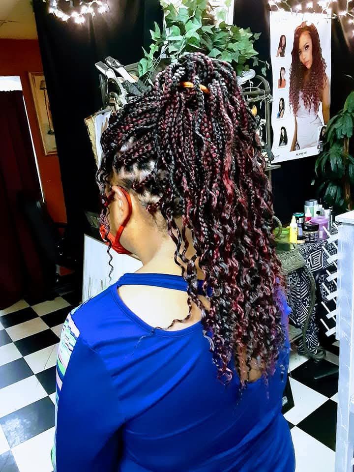A woman with braids and curly hair is wearing a blue shirt.