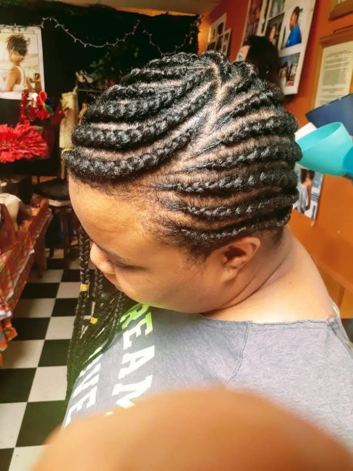 A woman with braids on her head is wearing a gray shirt.