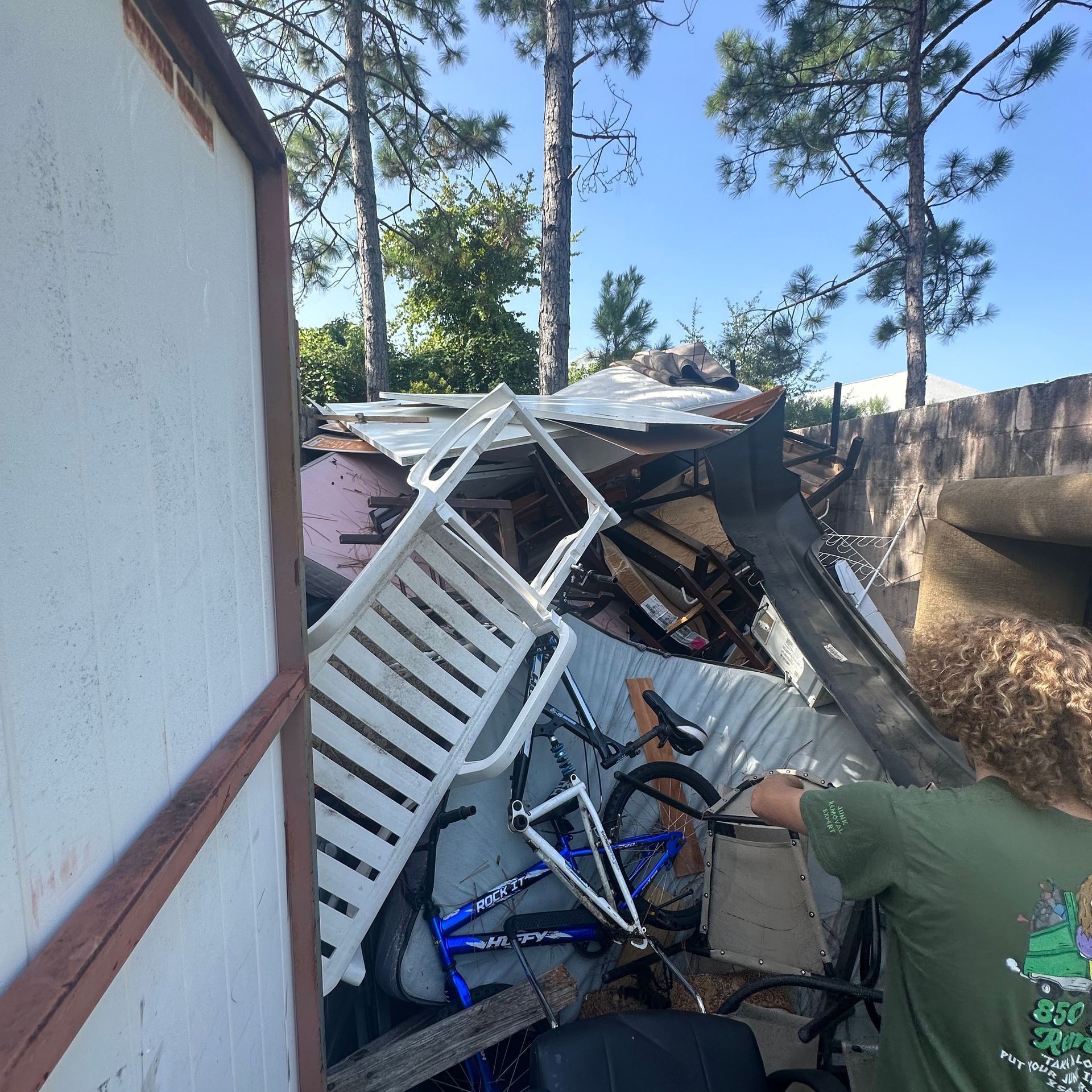 A man in a green shirt is standing in front of a pile of junk