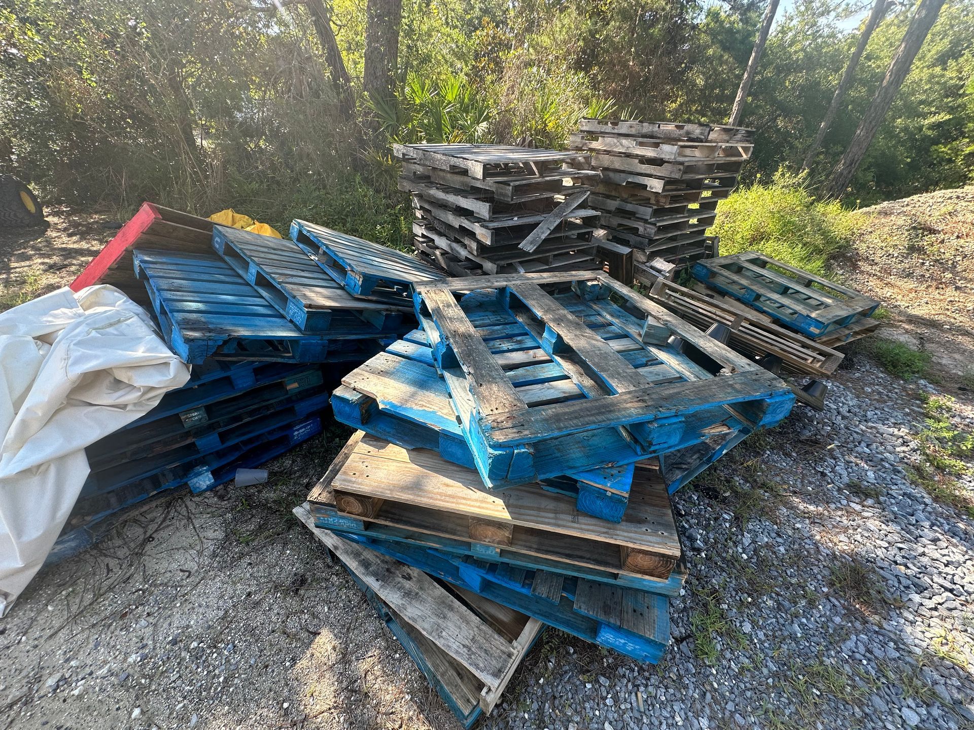 A pile of blue and brown wooden pallets are stacked on top of each other on the ground.