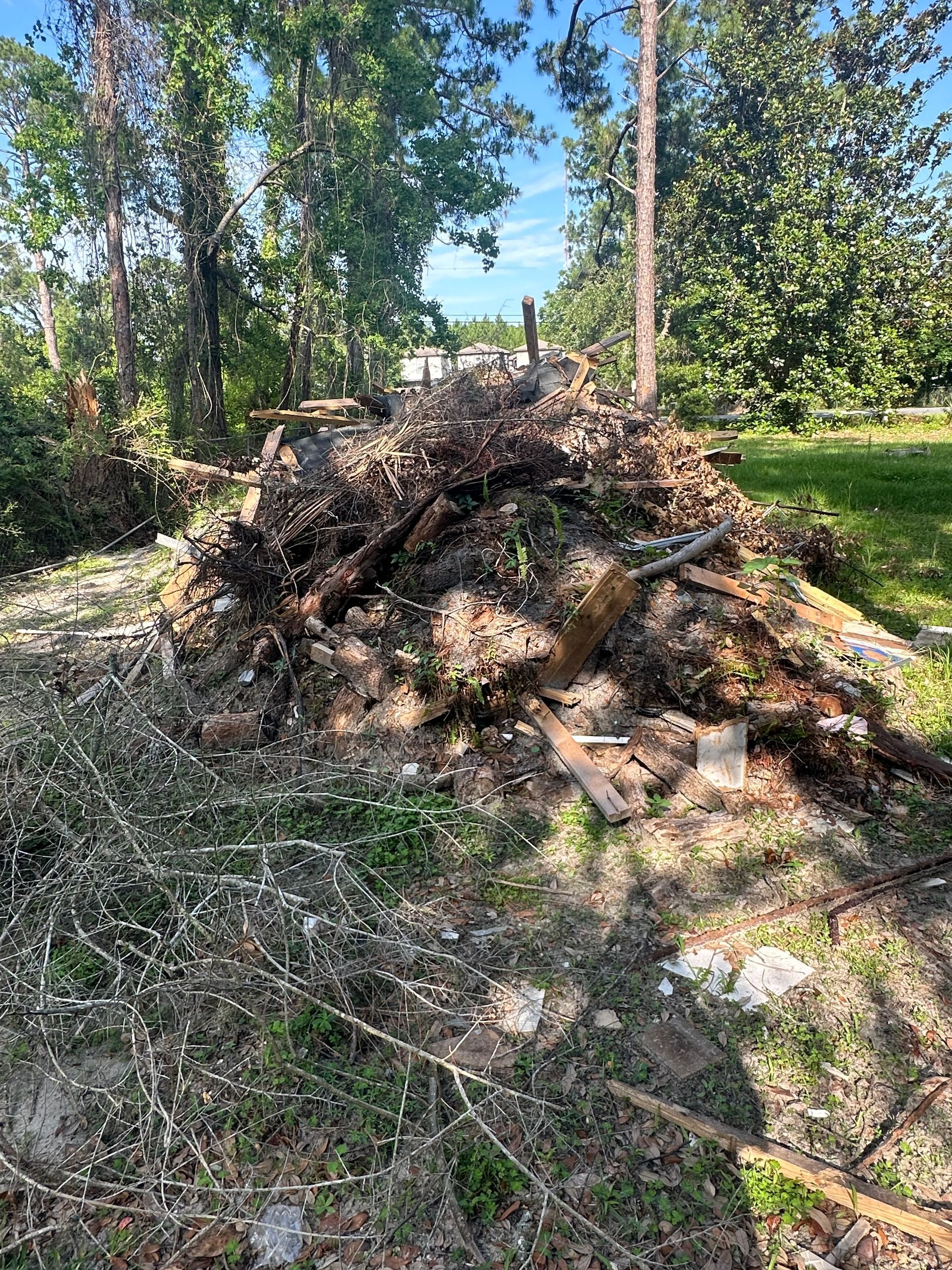 There is a large pile of wood in the middle of a field.