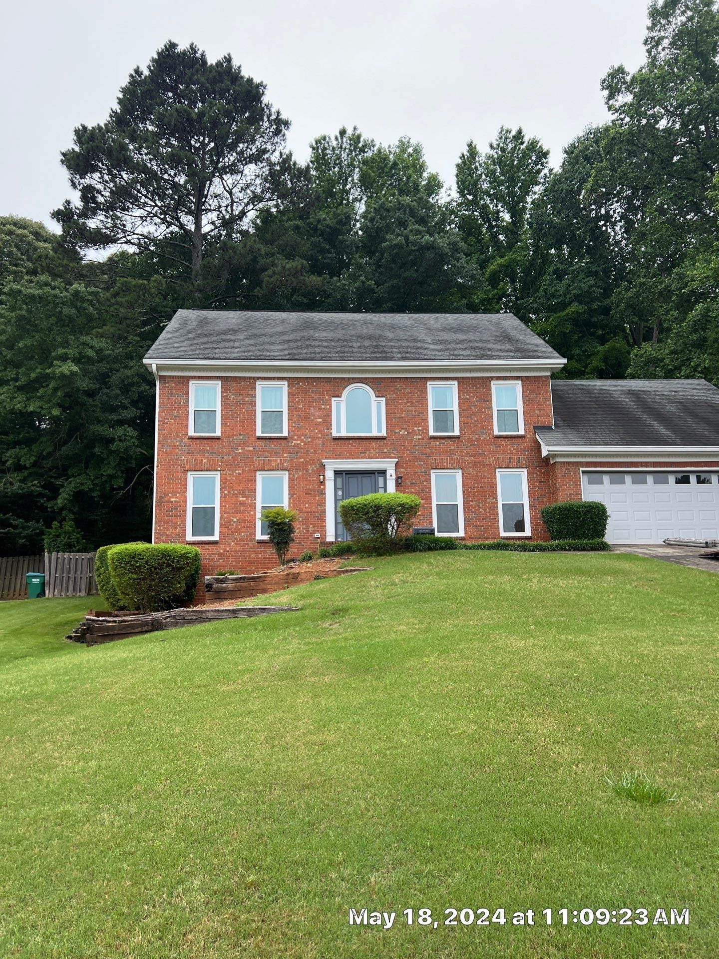 A large brick house with a lush green lawn in front of it.