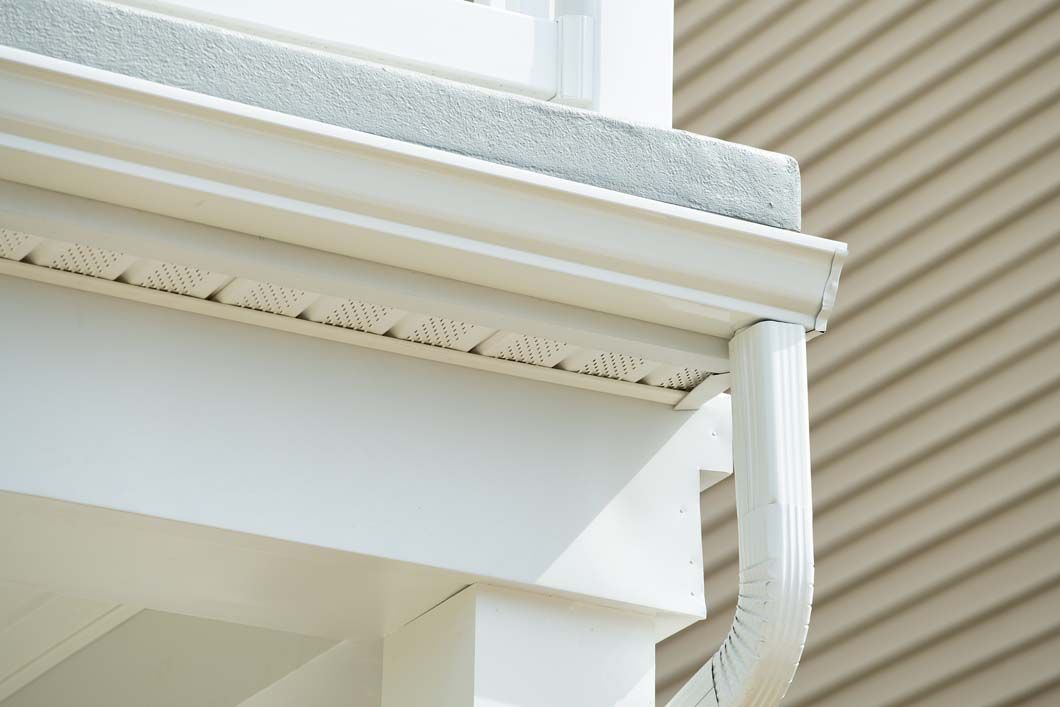 A close up of a white gutter on the side of a house.