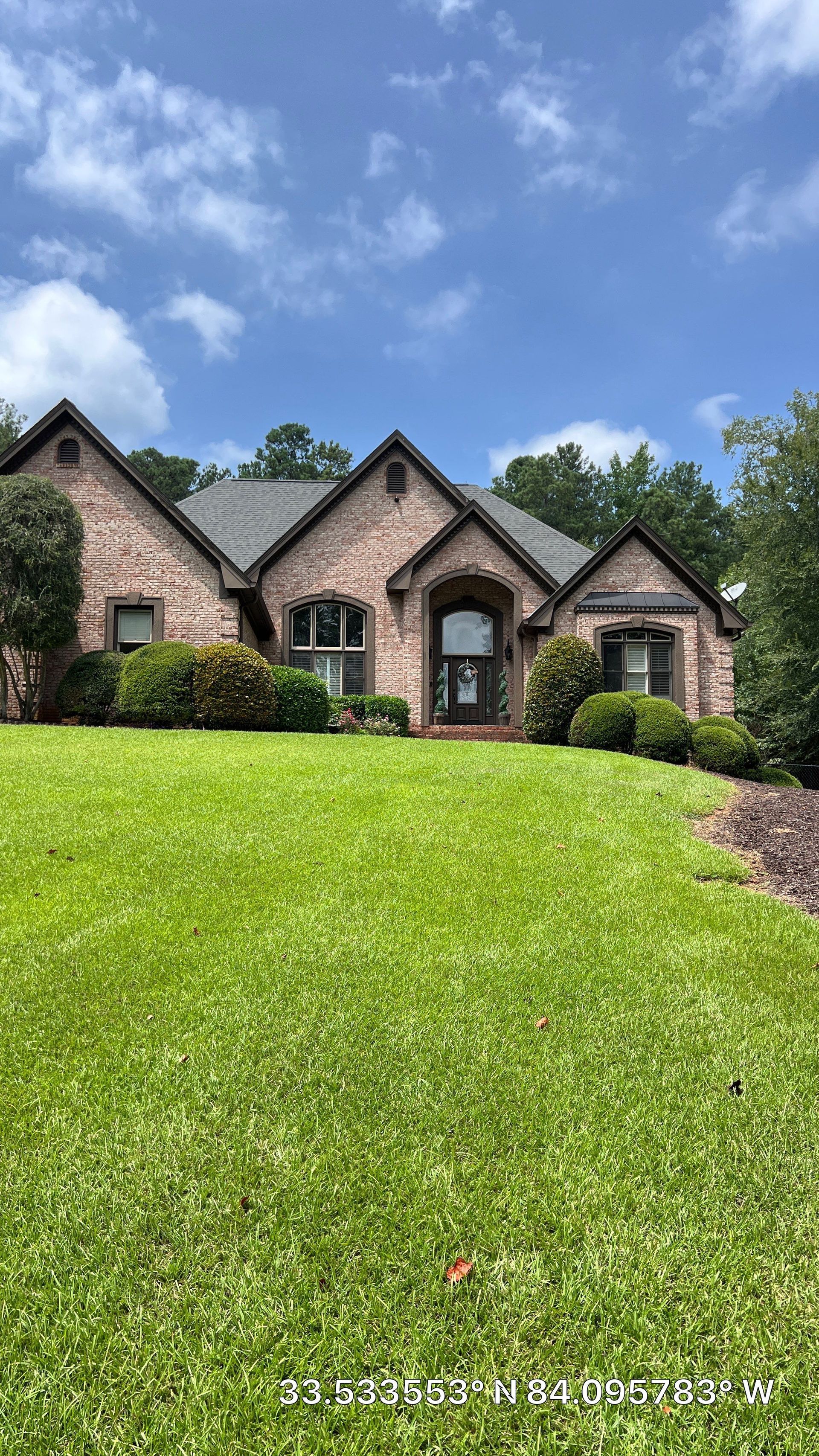 A large brick house with a lush green lawn in front of it.