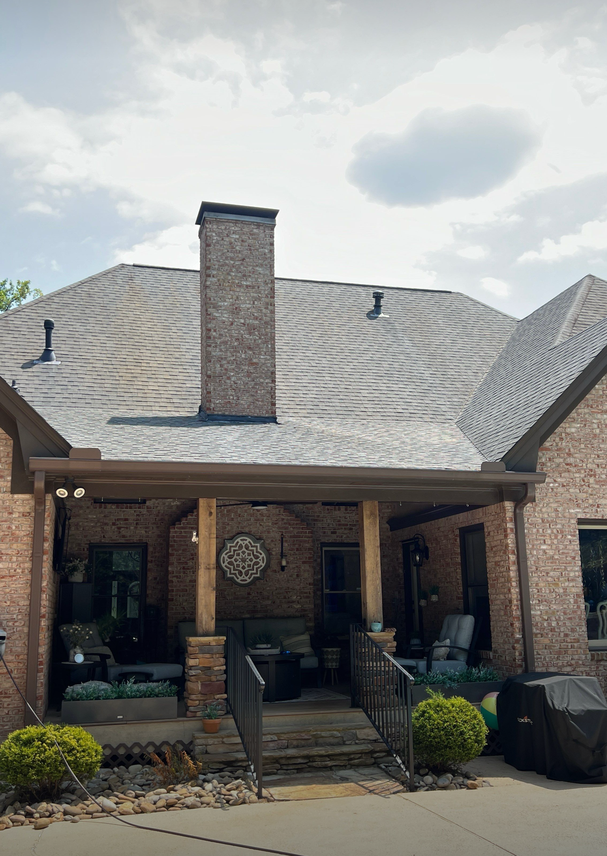 A brick house with a porch and a chimney on the roof