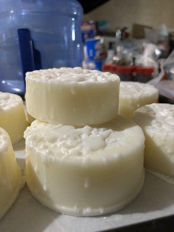 Round, white soaps stacked and arranged, on a surface, likely homemade.