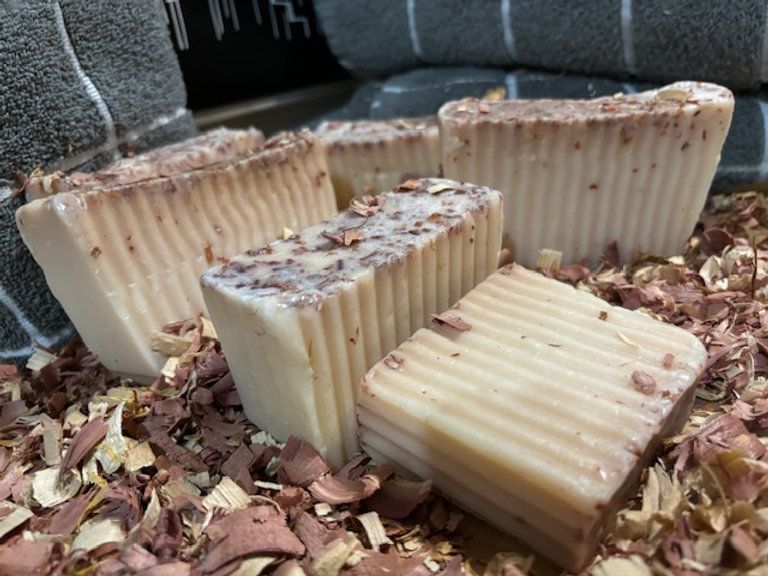 Five bars of textured soap with reddish flecks, on wood shavings.