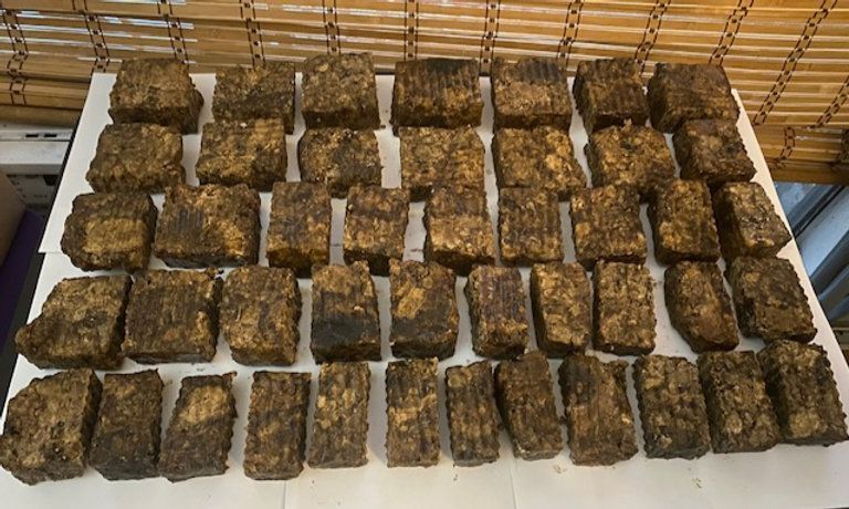 Arrangement of many brown, rectangular blocks, possibly soap, on a white surface.