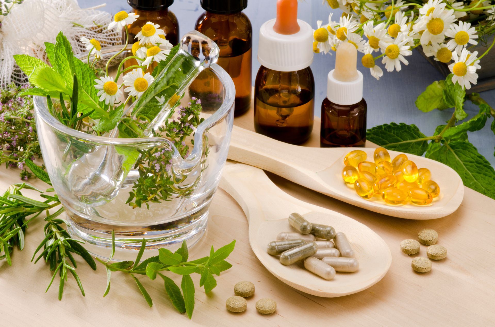 Herbs, bottles, and pills on wooden spoons, possibly related to natural medicine or remedies.