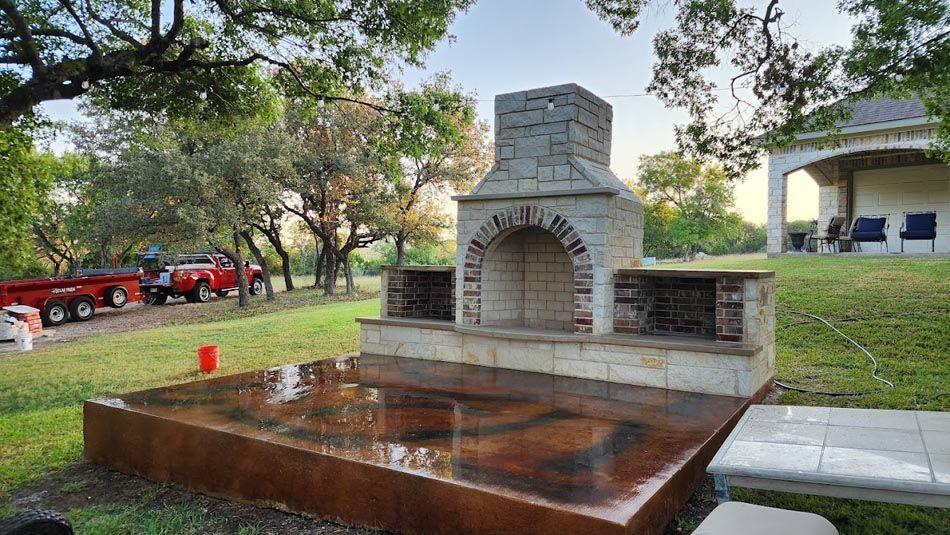 A Large Brick Fireplace Is Sitting in The Middle of A Lush Green Field