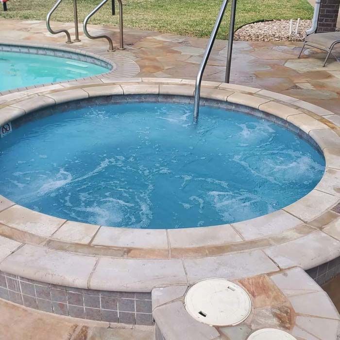 A Round Hot Tub Filled with Blue Water Next to A Swimming Pool
