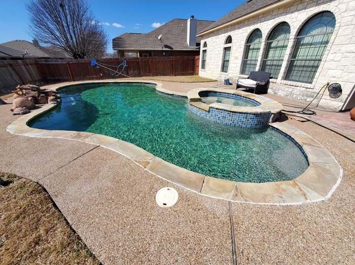 A Large Swimming Pool with A Hot Tub in The Backyard of A House