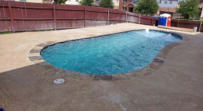A Large Swimming Pool with A Red Fence in The Background