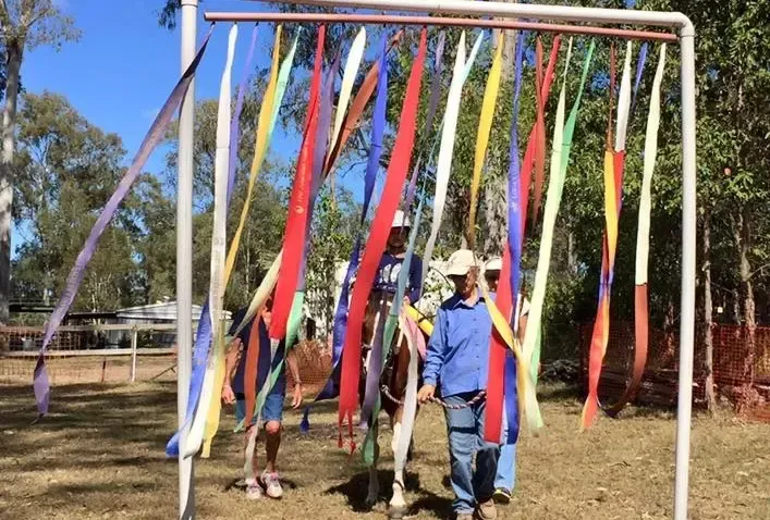 Horse and handler walking through colorful ribbons in a sunny outdoor setting.