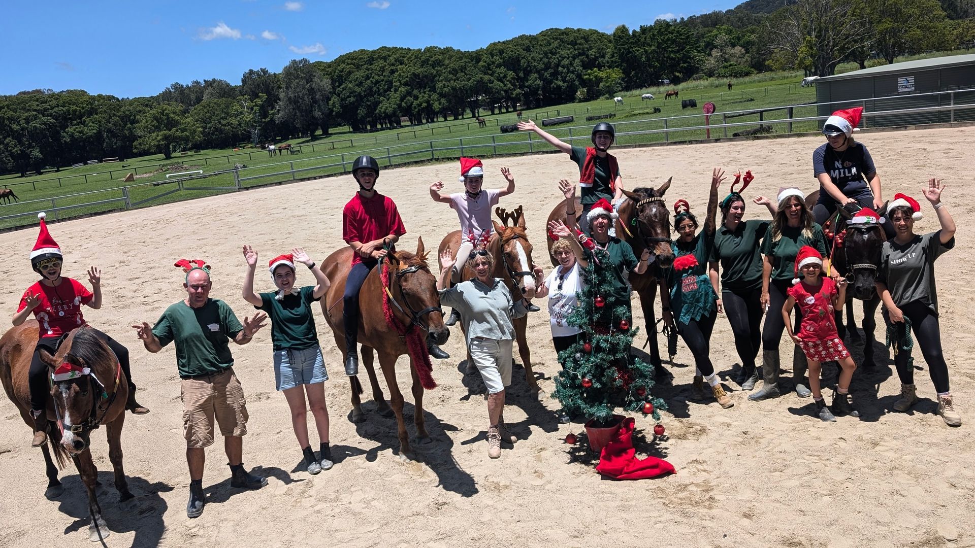 Group of people on horseback and on foot, wearing Santa hats, celebrating outdoors.