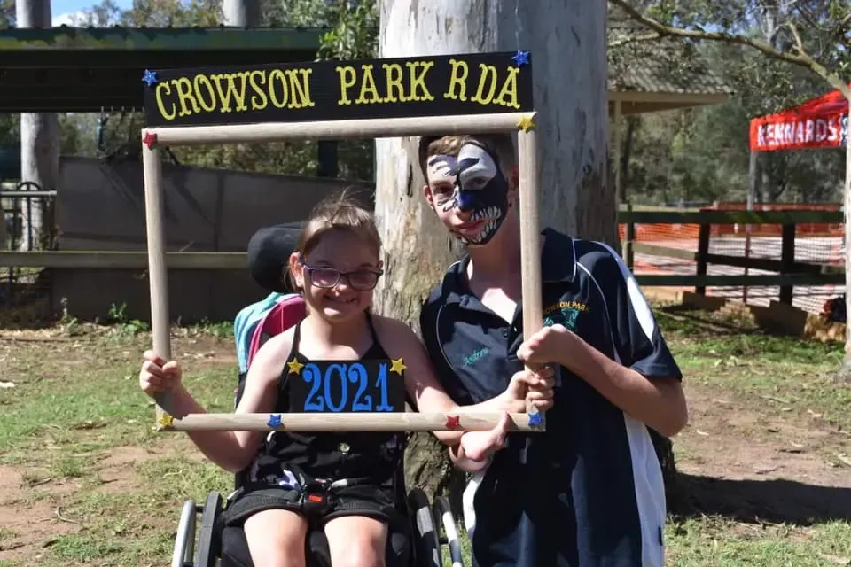 Two people at Crowson Park RDA with a cardboard frame; one in a wheelchair, holding