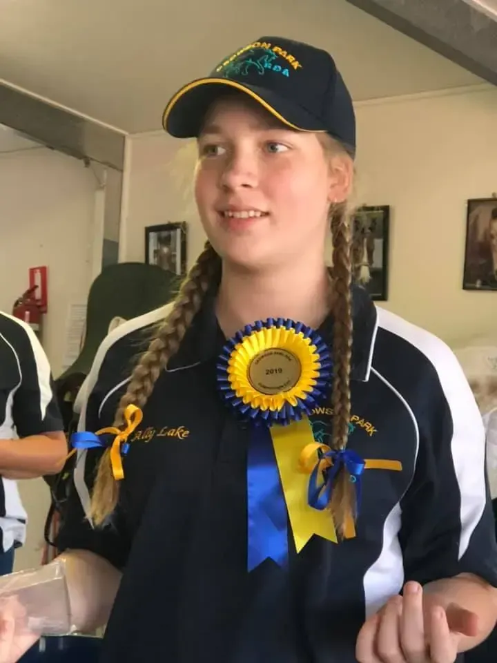 Girl in navy blue uniform and braids, wearing a hat and ribbon.