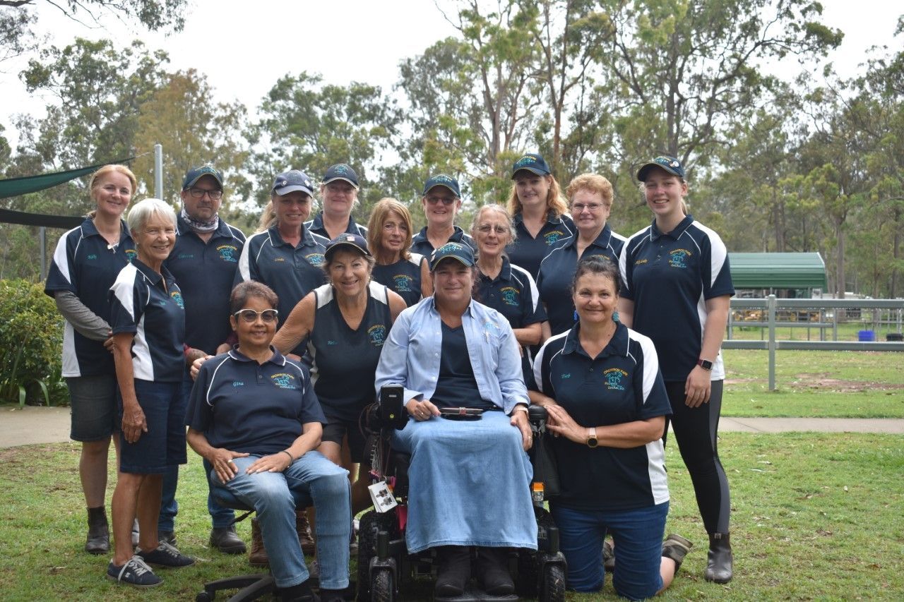 Group of people in matching shirts and hats pose outdoors.