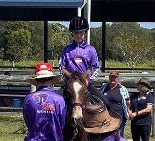 Person on horse, surrounded by people, in riding arena.