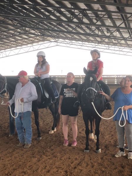 People riding horses indoors; adults leading.