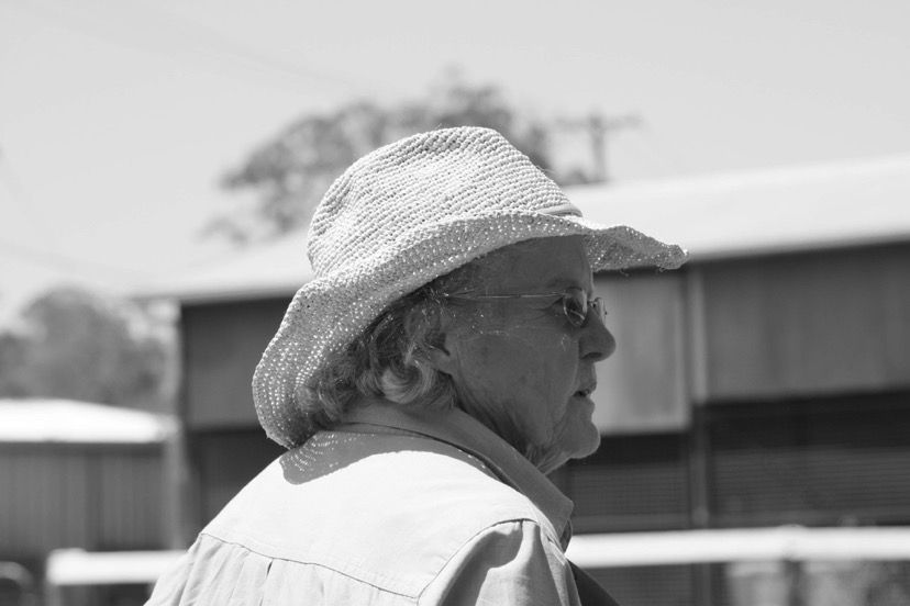 Person wearing a straw hat and glasses, looking to the right, outdoors.