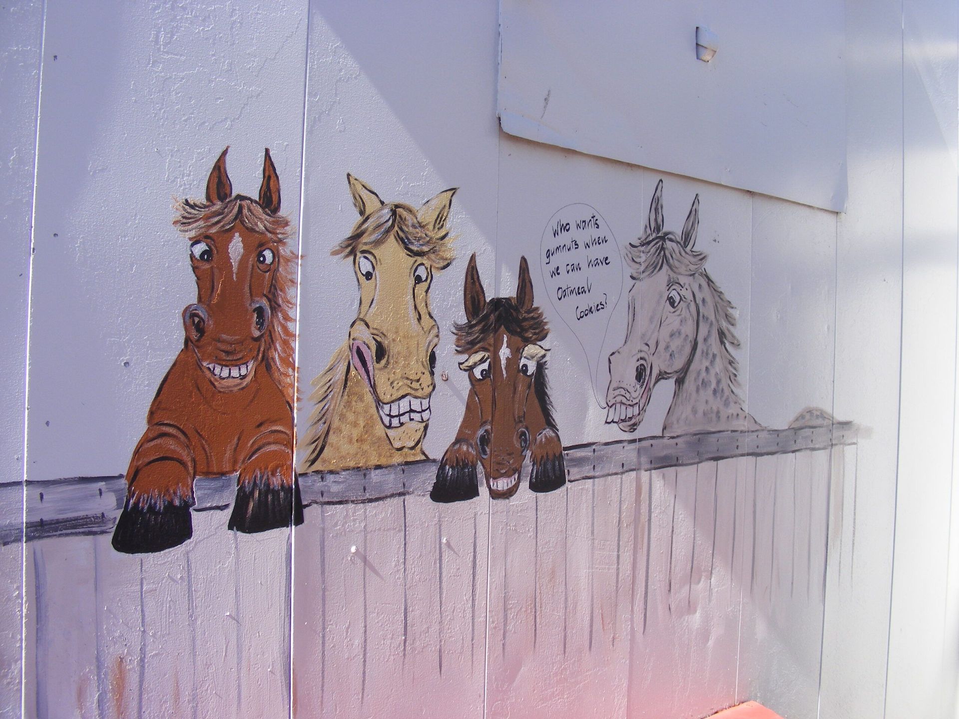 Four cartoon horses peeking over a fence; brown, tan, and gray colors; funny expressions.