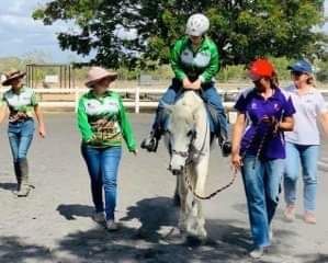 Group of people with a horse; one rides, others walk alongside in an outdoor setting.