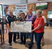 People holding a large check from the Hervey Bay Bar Fly Club, indoors.