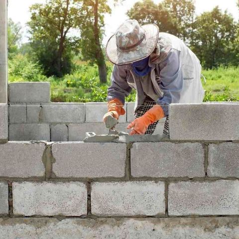 a man is laying bricks on a wall .