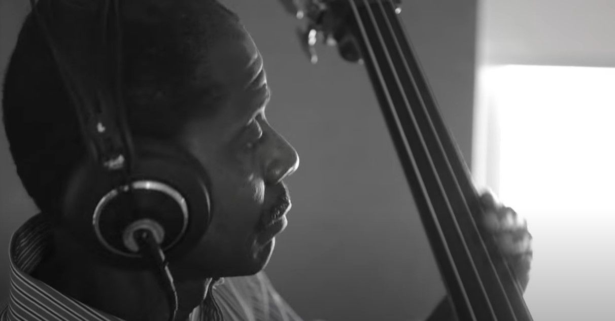 Avery Sharpe wearing headphones is playing a double bass